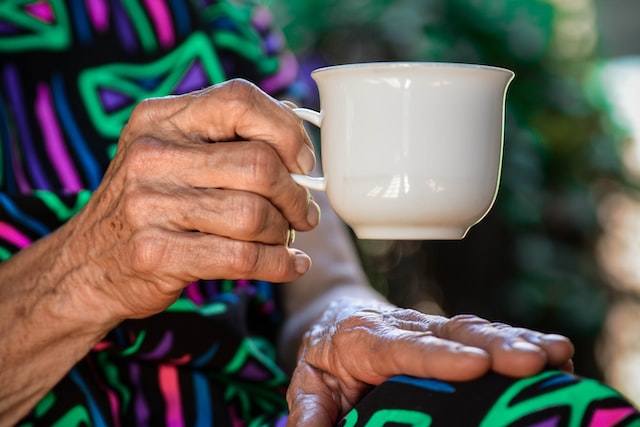 Main de femme âgée tenant une tasse